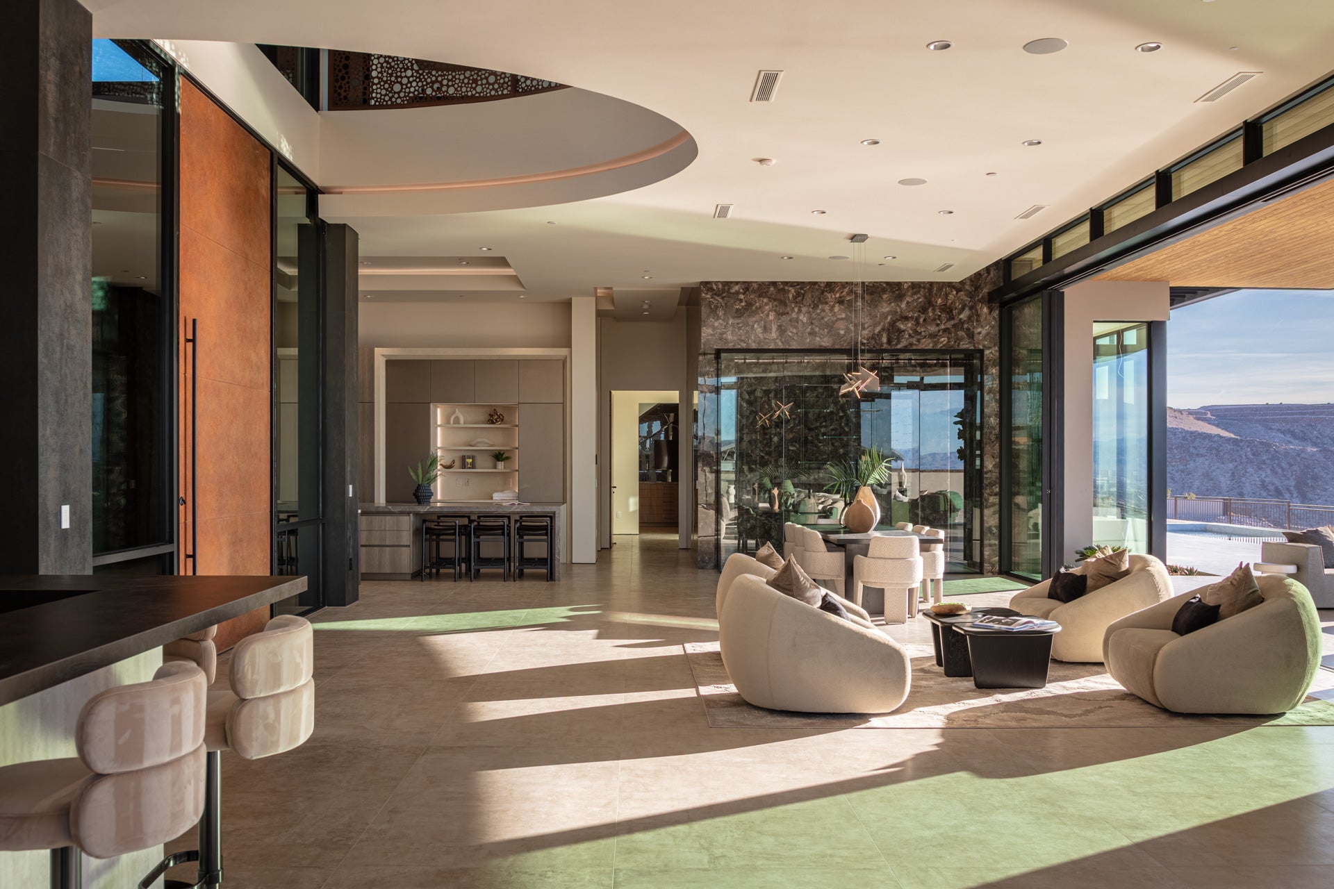 Modern open-plan living space with curved seating, large windows, and abundant natural light.

